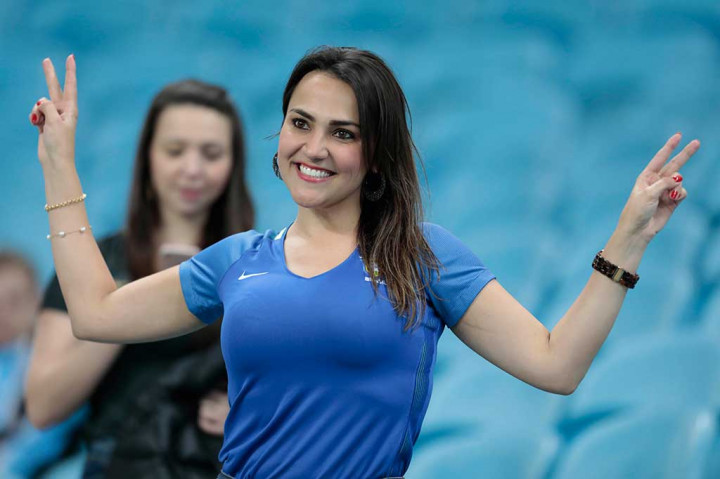 Seorang suporter wanita menyambut gembira kemenangan tim kesayangannya.