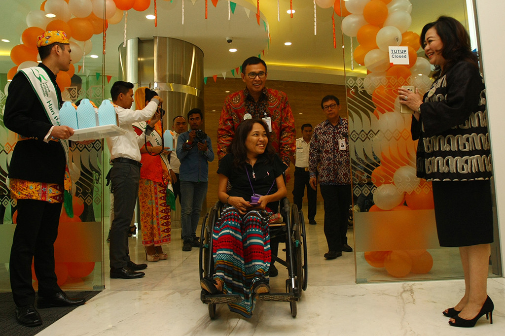 Dirut BNI Achmad Baiquni membantu mendorong kursi roda seorang nasabah penyandang disabilitas yang akan bertransaksi pada peringatan Hari Pelanggan Nasional 2017 di Kantor Cabang Pembantu BNI Serpong, Tangerang Selatan, Banten. ANTARA/Muhammad Iqbal