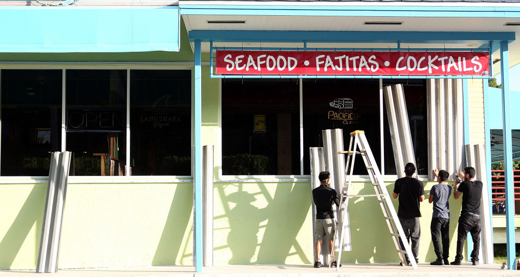 Pekerja sedang menutup kaca cendela rumah makan di Islamora, Florida, tempat mereka bekerja dengan lembaran baja ringan. Warga di pemukiman sekitar pantai Florida banyak yang telah mengungsi. Marc Serota/Getty Images/AFP Photo