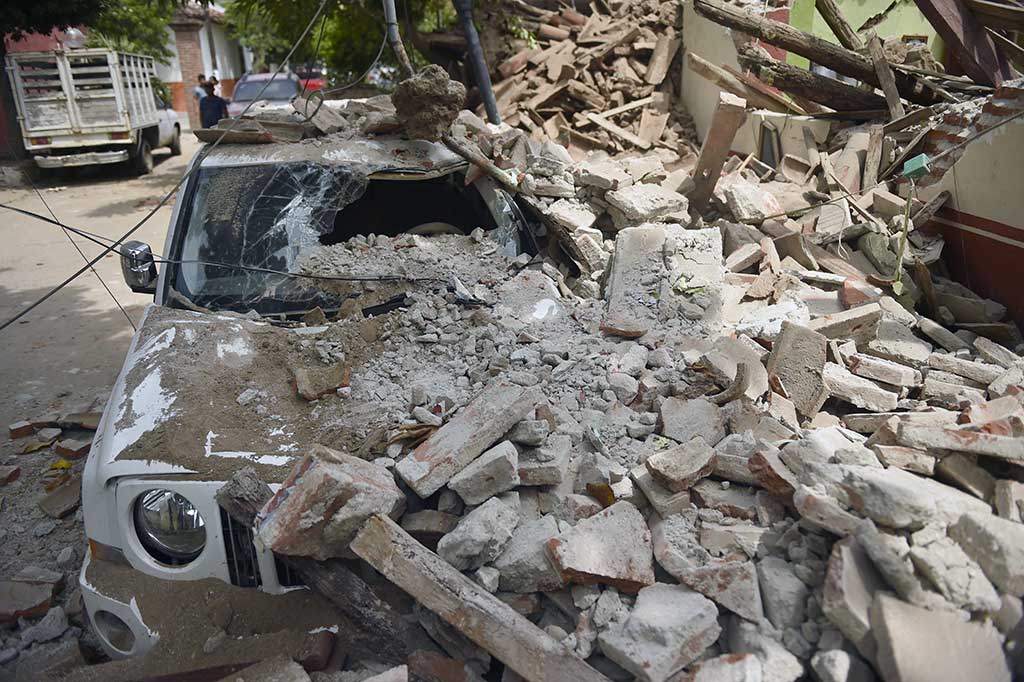 Sebuah mobil ringsek tertimpa bangunan yang runtuh. 