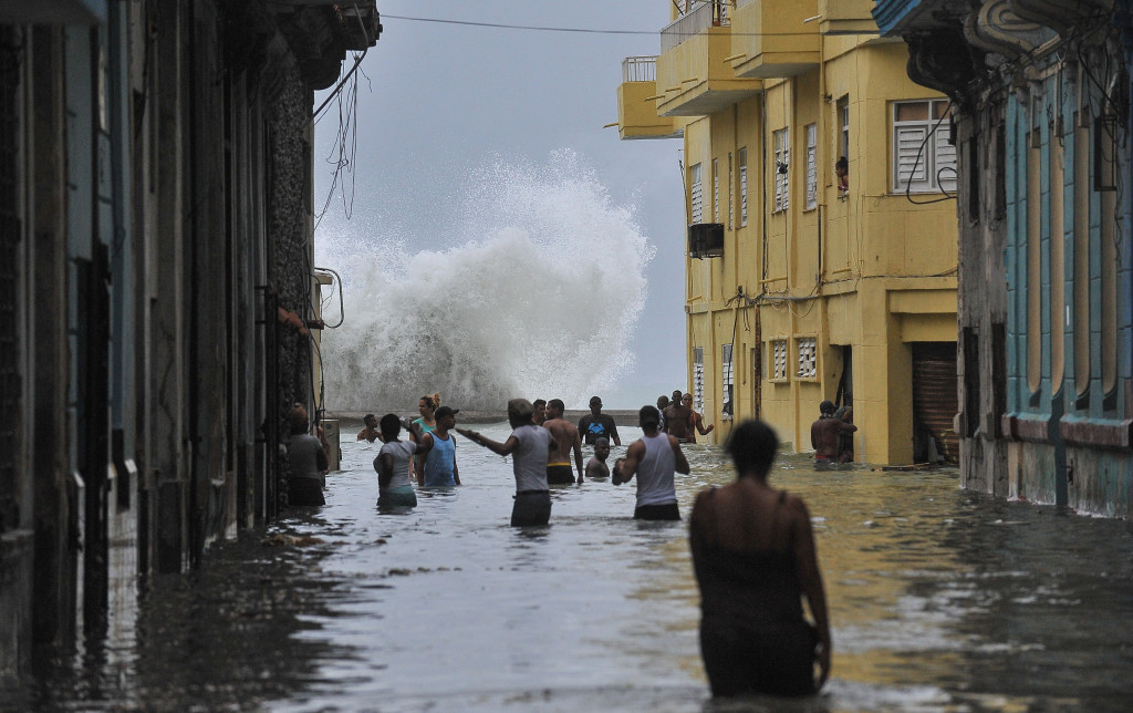 Hempasan lidah ombak laut di belakang warga Havana berjalan menembus banjir. Jutaan warga telah diungsikan sebelum badai datang untuk menekan jumlah korban jiwa.