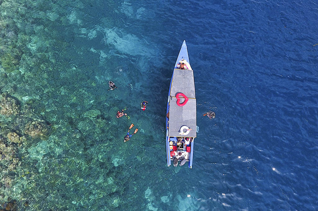 Pemandangan air laut yang jernih dihiasi perahu-perahu pembawa wisatawan yang berlabuh di Pulau Dodola, Kabupaten Morotai, Maluku Utara.