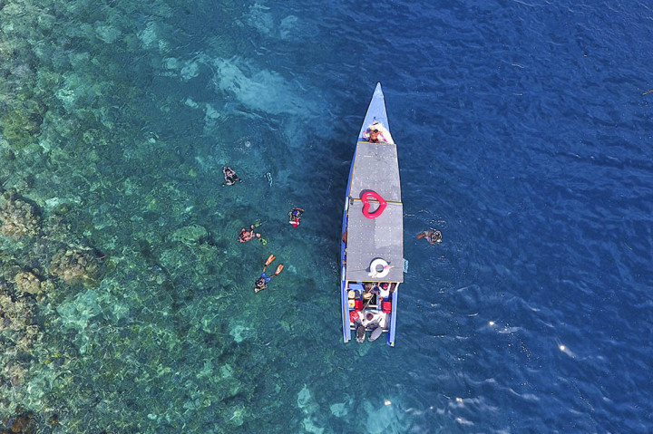 Pemandangan air laut yang jernih dihiasi perahu-perahu pembawa wisatawan yang berlabuh di Pulau Dodola, Kabupaten Morotai, Maluku Utara.