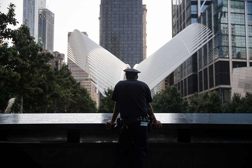Seorang anggota New York City Police Department (NYPD) termangu sejenak di depan National September 11 Memorial, saat mengenang para korban serangan 11 September.