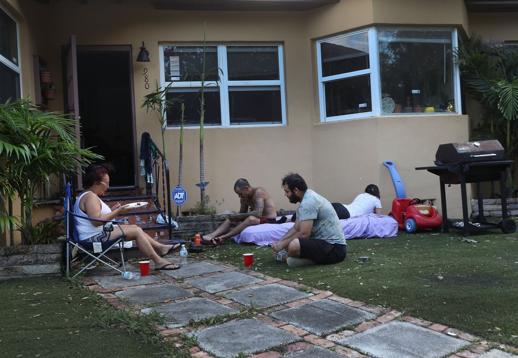 Keluarga di Miami, Florida, memilih berkumpul halaman rumahnya pada sore hari untuk mendapatkan udara sejuk. Pada siang hari udara sangat panas, sementara aliran listrik yang dibutuhkan untuk menyalakan pendingin ruangan masih terputus. Joe Raedle/Getty Images/AFP