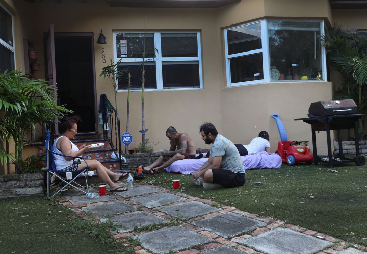 Keluarga di Miami, Florida, memilih berkumpul halaman rumahnya pada sore hari untuk mendapatkan udara sejuk. Pada siang hari udara sangat panas, sementara aliran listrik yang dibutuhkan untuk menyalakan pendingin ruangan masih terputus. Joe Raedle/Getty Images/AFP