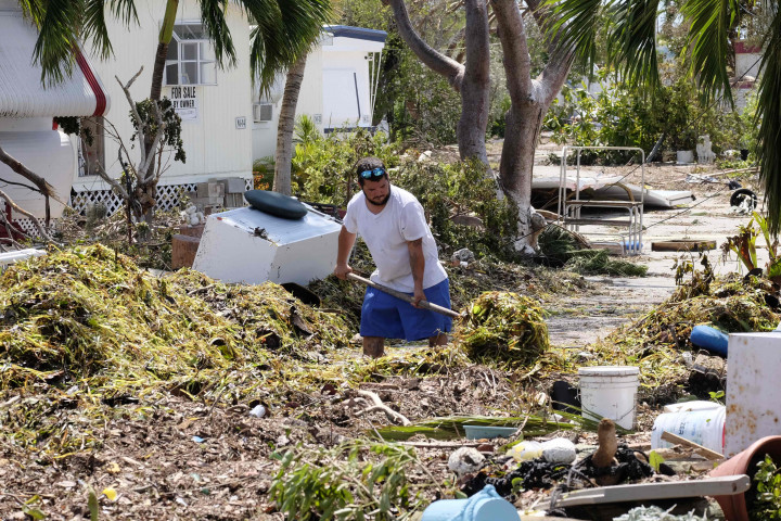 Martin berusaha membersihkan timbunan rumput laut yang memenuhi halaman rumanya di Tavenier Key, Florida. Rumput laut sebanyak itu terbawa dari laut olah angin badai Irma yang kecepatannya hampir mencapi 300 kilometer per jam. AFP Photo/Gaston De Cardenas