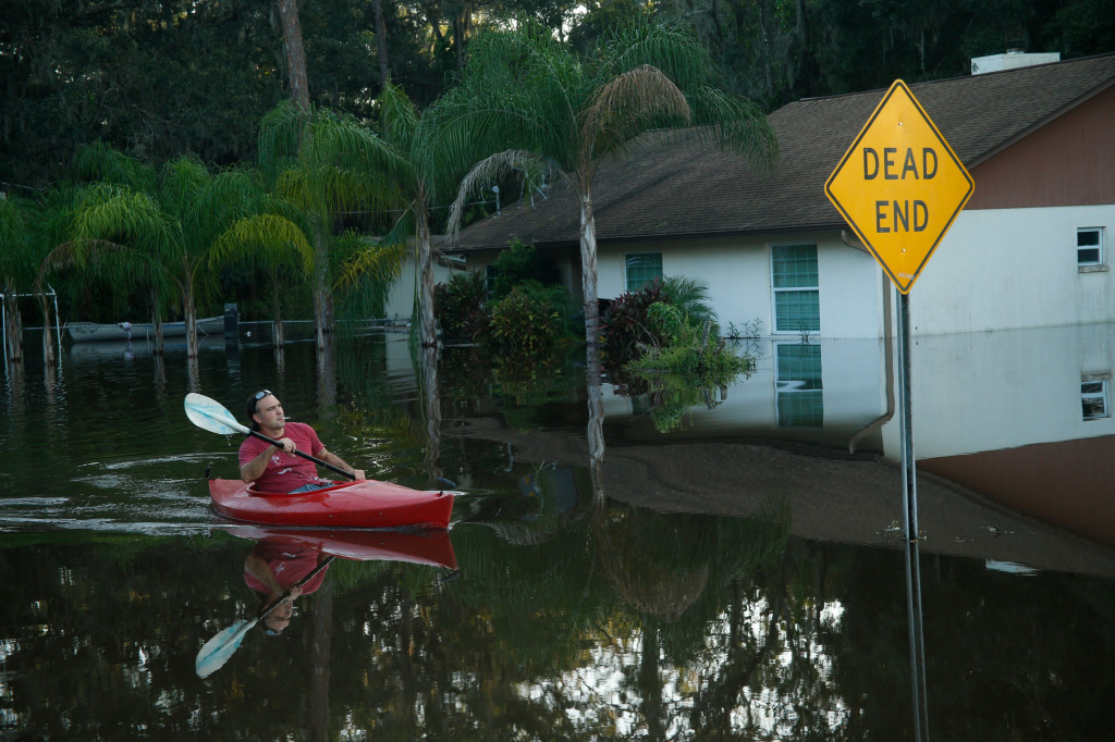 Di beberapa tempat, banjir belum sepenuhnya surut. Warga hanya dapat memeriksa kondisi luar rumahnya dengan menggunakan sampan. Seperti di Alvarico, Florida, ini. Brian Blanco/Getty Images/AFP
