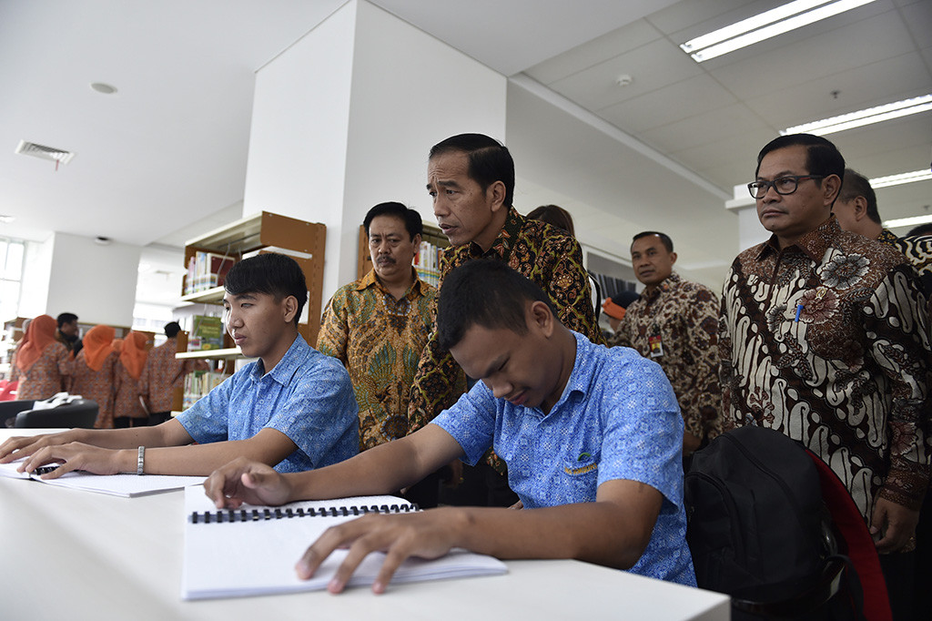 Presiden Joko Widodo didampingi Kepala Perpustakaan Nasional Muh Syarif Bando dan Seskab Pramono Anung mendengarkan cerita yang dibacakan oleh siswa penyandang disabilitas disela-sela peresmian Gedung Fasilitas Perpustakaan Nasional.
