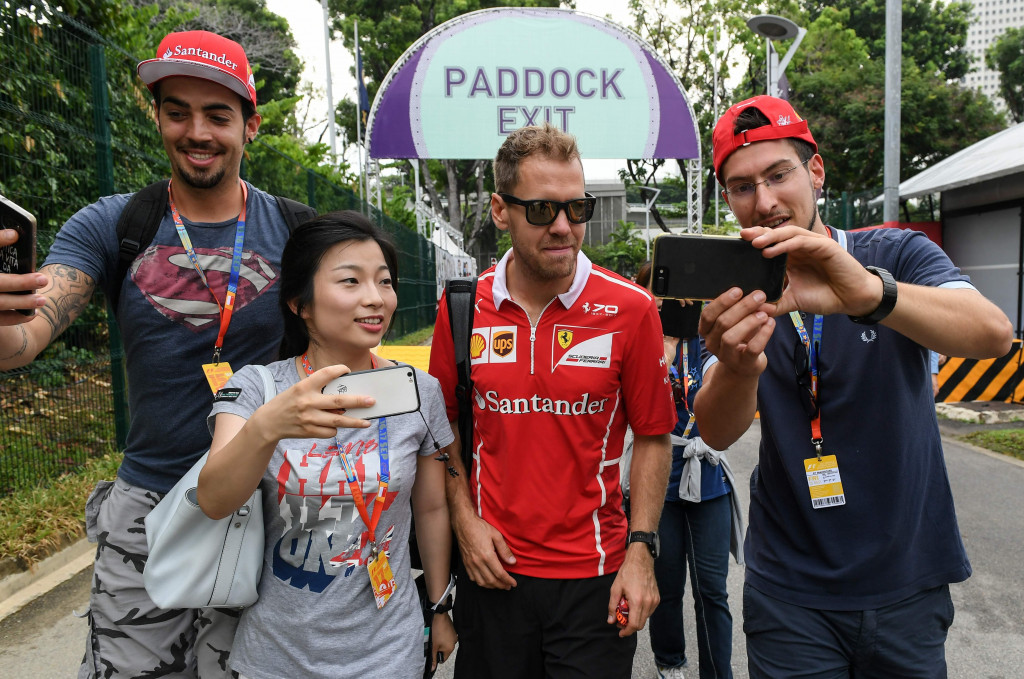 Sebastian Vettel, pembalap Ferrari, melayani ajakan swafoto para penggemarnya yang mencegat di pintu masuk sirkuit Marina Bay.