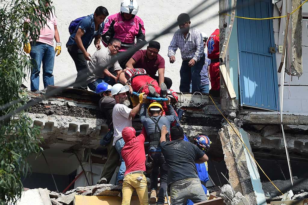 Petugas dengan penuh kehati-hatian mengevakuasi korban luka-luka dari reruntuhan gedung.