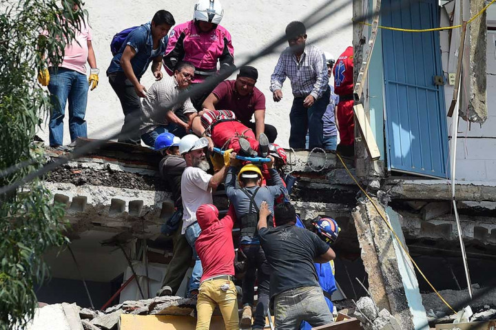 Petugas dengan penuh kehati-hatian mengevakuasi korban luka-luka dari reruntuhan gedung.