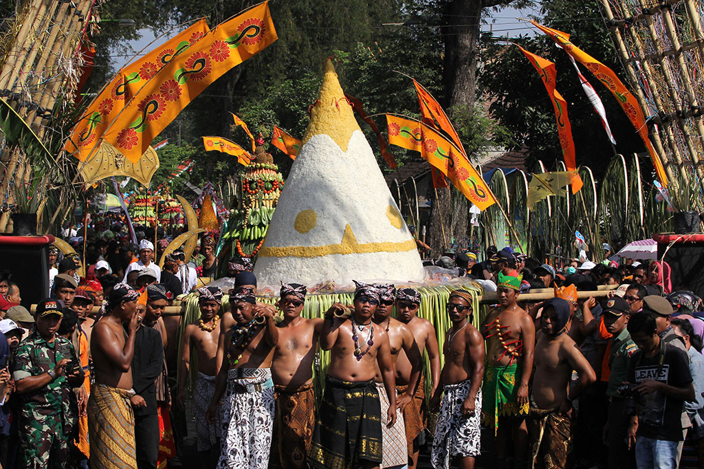 Warga mengarak tumpeng raksasa berkeliling kampung di Pekulo, Banyuwangi, Jawa Timur, Rabu (20/9/2017). Sebanyak 20 tumpeng raksasa dan gunungan hasil bumi itu, diarak untuk menyambut perganian tahun Islam (Muharam) atau dalam kalender Jawa dikenal dengan bulan Suro.