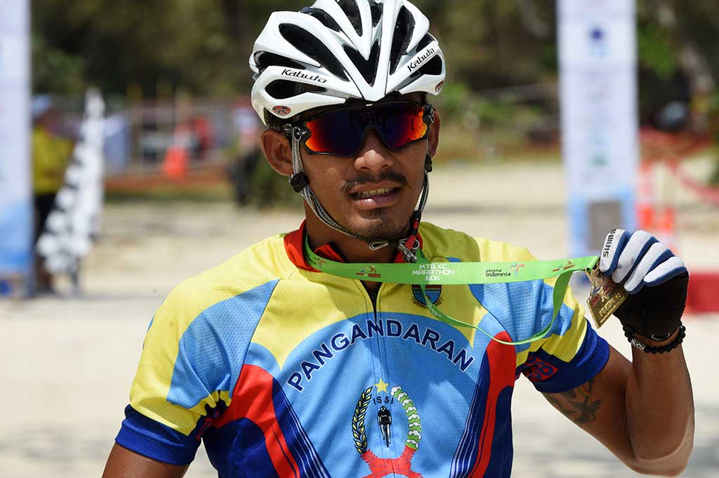 Atlet sepeda ISSI Pangandaran Chandra Rafsanzani memperlihatkan medali usai finis tercepat pada Mountain Bike Cross Country Maraton (MTB-XCM) di Tanjung Lesung, Pandeglang, Banten, Sabtu (23/9/2017).