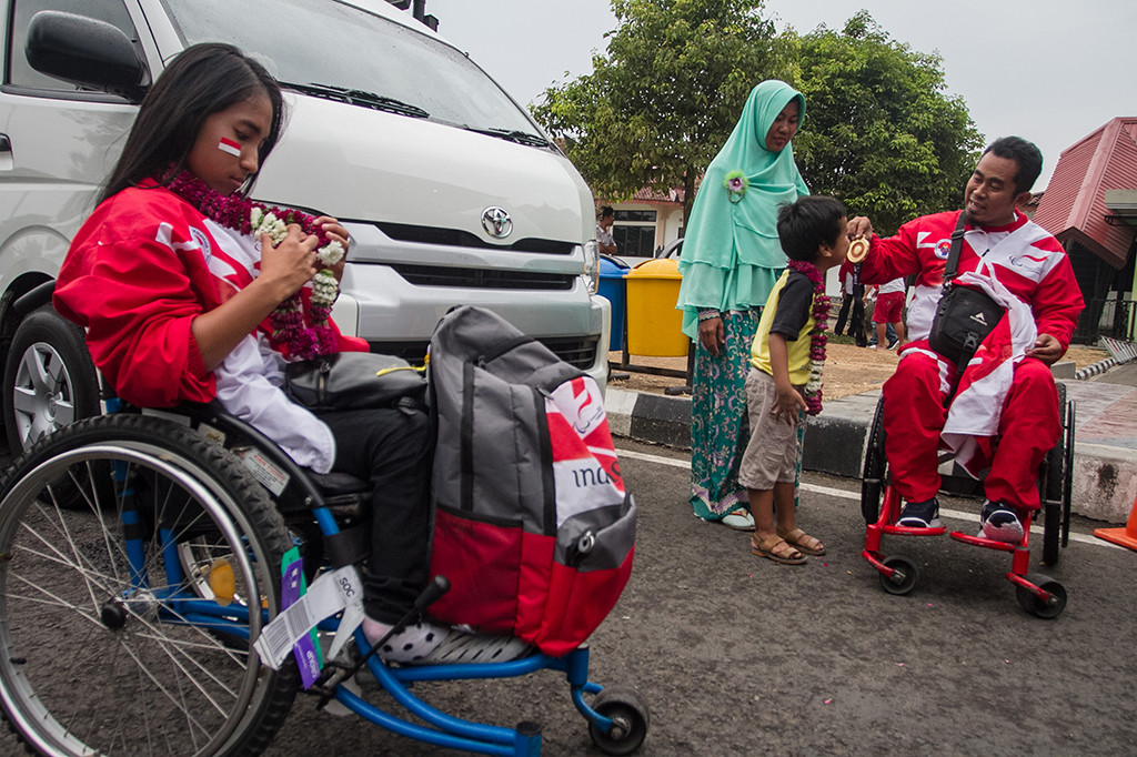 Atlet Tenis Meja National Paralympic Committee (NPC) Edi Nuryanto (kanan) menunjukkan medali emas kepada anaknya saat tiba di Bandara Adi Soemarmo, Boyolali, Jawa Tengah.