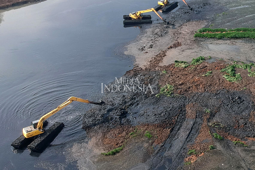Petugas dengan alat berat mengeruk endapan lumpur di Waduk Ria Rio, Kayu Putih, Pulo Gadung, Jakarta.