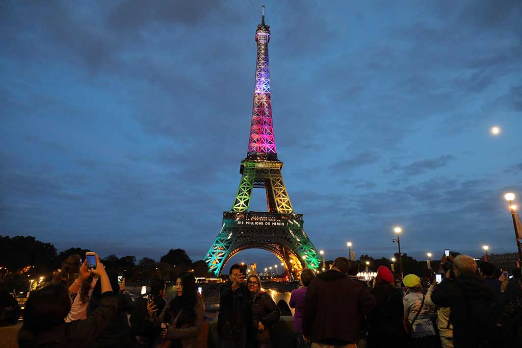Pengunjung berfoto dengan latar belakang Menara Eiffel yang diterangi dengan huruf bertuliskan '300 juta terima kasih', untuk merayakan 300 juta pengunjung sejak dibuka pada 1889, Kamis (28/9/2017) waktu setempat.