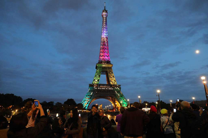 Pengunjung berfoto dengan latar belakang Menara Eiffel yang diterangi dengan huruf bertuliskan '300 juta terima kasih', untuk merayakan 300 juta pengunjung sejak dibuka pada 1889, Kamis (28/9/2017) waktu setempat.