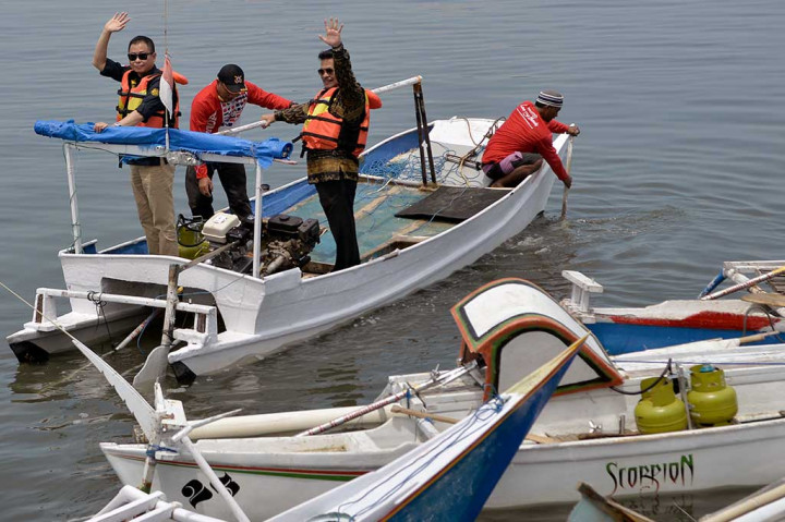 Menteri Energi dan Sumber Daya Mineral Ignasius Jonan (kiri) dan Gubernur Sulsel Syahrul Yasin Limpo melambaikan tangan di atas perahu saat mencoba penggunaan paket perdana konversi BBM ke BBG di Anjungan Losari, Makassar, Sulawesi Selatan, Jumat (29/9/2017).