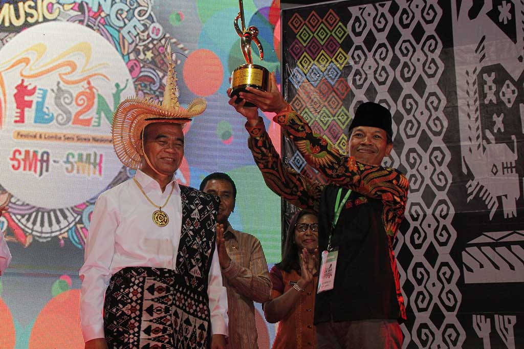 Mendikbud Muhadjir Effendy (kiri) memberikan piala bergilir kepada perwakilan Provinsi DIY Yogyakarta yang menjadi juara umum Festival dan Lomba Seni Siswa Nasional (FLS2N) di Kupang, NTT Jumat (29/9/2017).