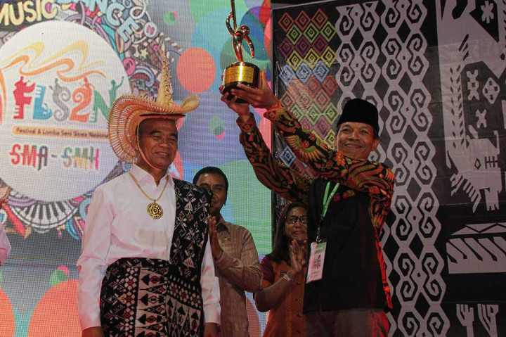 Mendikbud Muhadjir Effendy (kiri) memberikan piala bergilir kepada perwakilan Provinsi DIY Yogyakarta yang menjadi juara umum Festival dan Lomba Seni Siswa Nasional (FLS2N) di Kupang, NTT Jumat (29/9/2017).