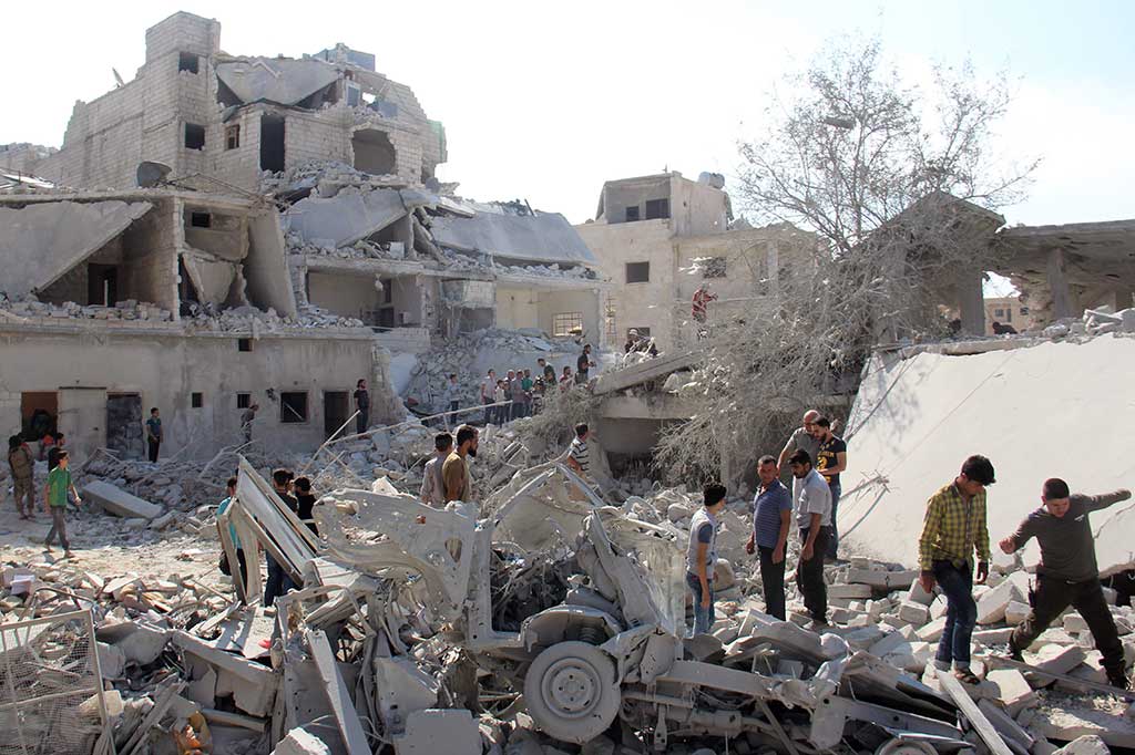 Warga Suriah mencari korban di antara reruntuhan bangunan menyusul serangan udara di kota pemberontak Armanaz, di Provinsi Idlib dekat perbatasan Turki, Sabtu (30/9/2017). Serangan terjadi pada Jumat (29/9/2017) malam waktu setempat.