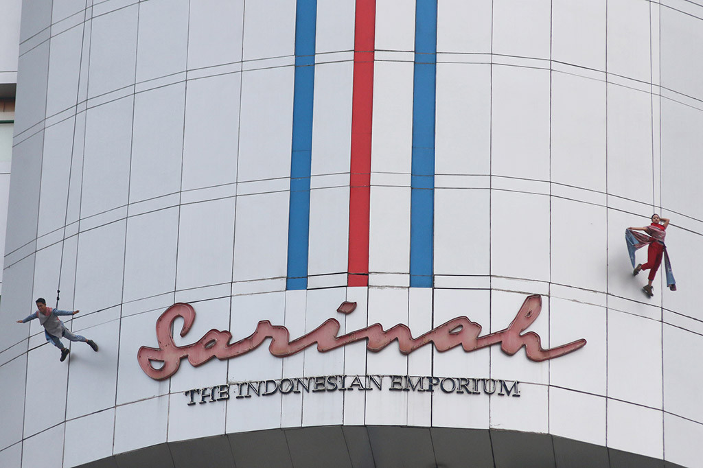 Seorang model berbusana batik menuruni gedung Sarinah saat melakukan atraksi 