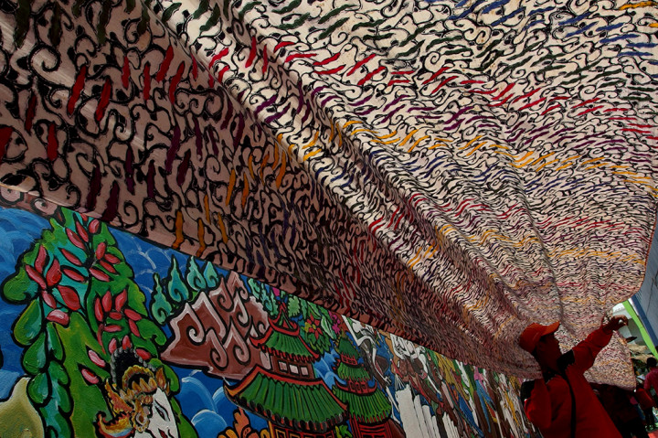 Warga membentangkan kain batik bermotif parang asem arang, saat memperingati Hari Batik Nasional di Kampung Batik Semarang, Jawa Tengah. Pembuatan kain batik sepanjang 33 meter tanpa sambungan tersebut dikerjakan oleh 10 orang pembatik selama enam bulan. ANTARA/R. Rekotomo