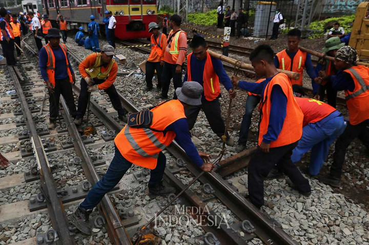 Petugas bekerja keras membenahi rel agar bisa dilalui kereta lagi