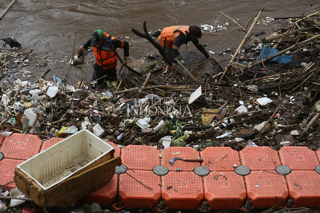 Petugas membersihkan tumpukan sampah dan potongan kayu yang tersangkut di aliran sungai Ciliwung, Pintu Air Manggarai, Jakarta.
