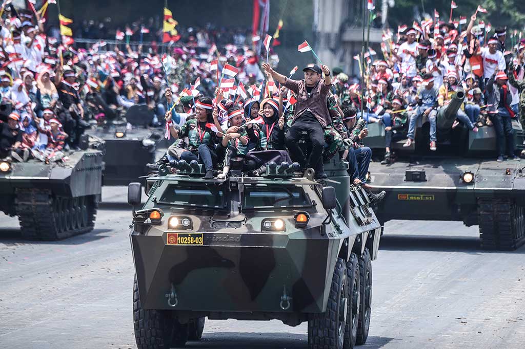 Warga menaiki kendaraan lapis baja milik TNI saat perayaan HUT ke-72 TNI di Dermaga Indah Kiat, Cilegon.
