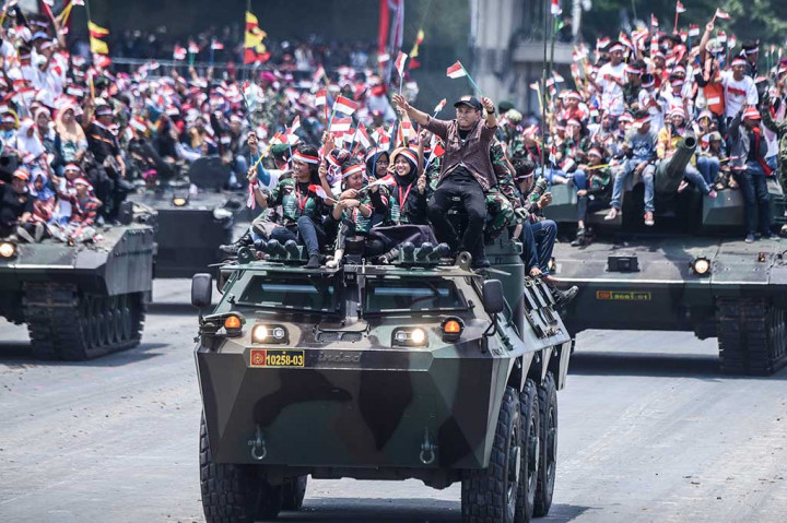 Warga menaiki kendaraan lapis baja milik TNI saat perayaan HUT ke-72 TNI di Dermaga Indah Kiat, Cilegon.
