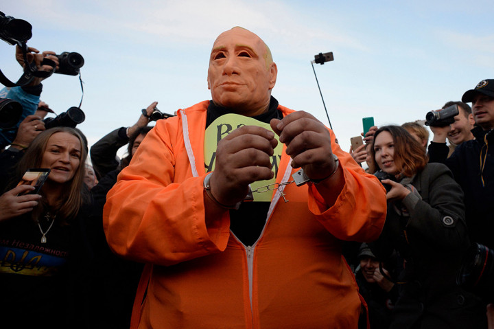 Demonstran mengenakan topeng karet yang menggambarkan Presiden Rusia Vladimir Putin