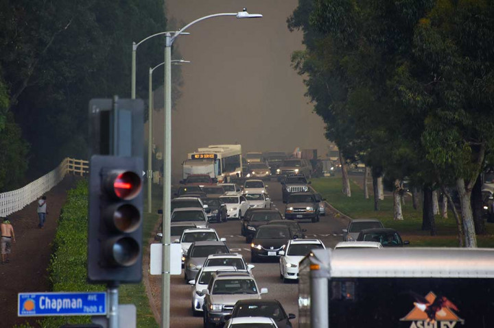 Kemacetan terjadi saat warga berbondong-bondong meninggalkan rumah mereka untuk mengungsi di Orange, California. Terlihat asap hitam pekat akibat kebakaran hutan di latar belakang. AFP/Robyn Beck