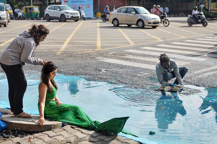 Seorang model dengan berbakaian seperti putri duyung ambil bagian dalam seni instalasi seniman Baadal Nanjundawsamy, Jumat 13/10/2017). Hal ini untuk memprotes banyaknya jalan berlubang di Bangalore.