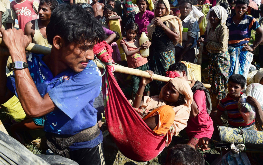 Perjalanan warga menyelamatkan diri dari konflik bersenjata di Rakhine, Myanmar, memang berat. Para manula dan sakit keras yang ikut mengungsi harus ditandu.