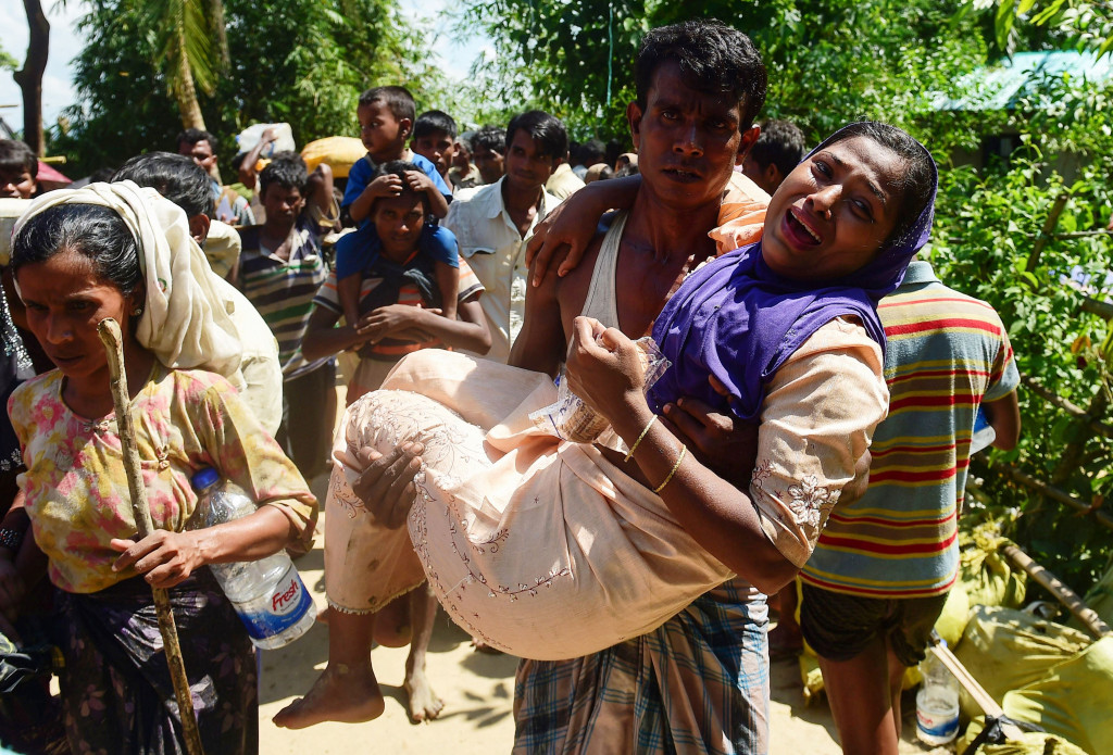 Seorang pengungsi menggendong kerabatnya yang terluka. Mereka berdua adalah pengungsi penumpang perahu yang selamat dari musibah.