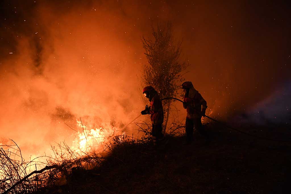 Petugas pemadam kebakaran berusaha memadamkan api yang membakar semak-semak di Cabanoes dekat Louzan, saat kebakaran hutan terus berlanjut di Portugal pada Senin (16/10/2017) waktu setempat. AFP/Francisco Leong