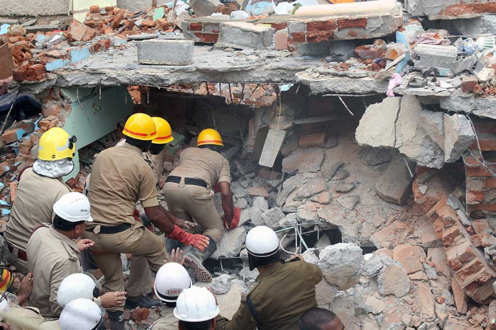 Personel penyelamatan India dari Dinas Pemadam Kebakaran dan Pasukan Penanggulangan Bencana Nasional berusaha mencari korban di antara puing-puing bangunan perumahan dua lantai ambruk di Ejipura, Bangalore, Senin (16/10/2017).