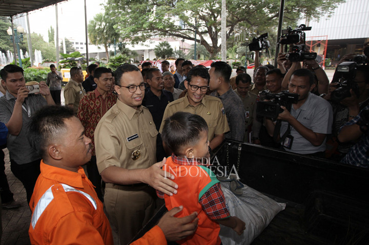 Setiba di halaman Balai Kota, Anies dan Sandi menyapa petugas kebersihan yang sedang membersihkan halaman dan membawa anak.
