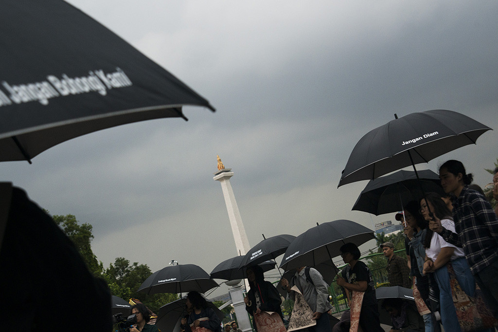 Para aktivis yang tergabung dalam Jaringan Solidaritas Korban untuk Keadilan (JSKK) melakukan aksi Kamisan di Silang Monas, Jakarta.
