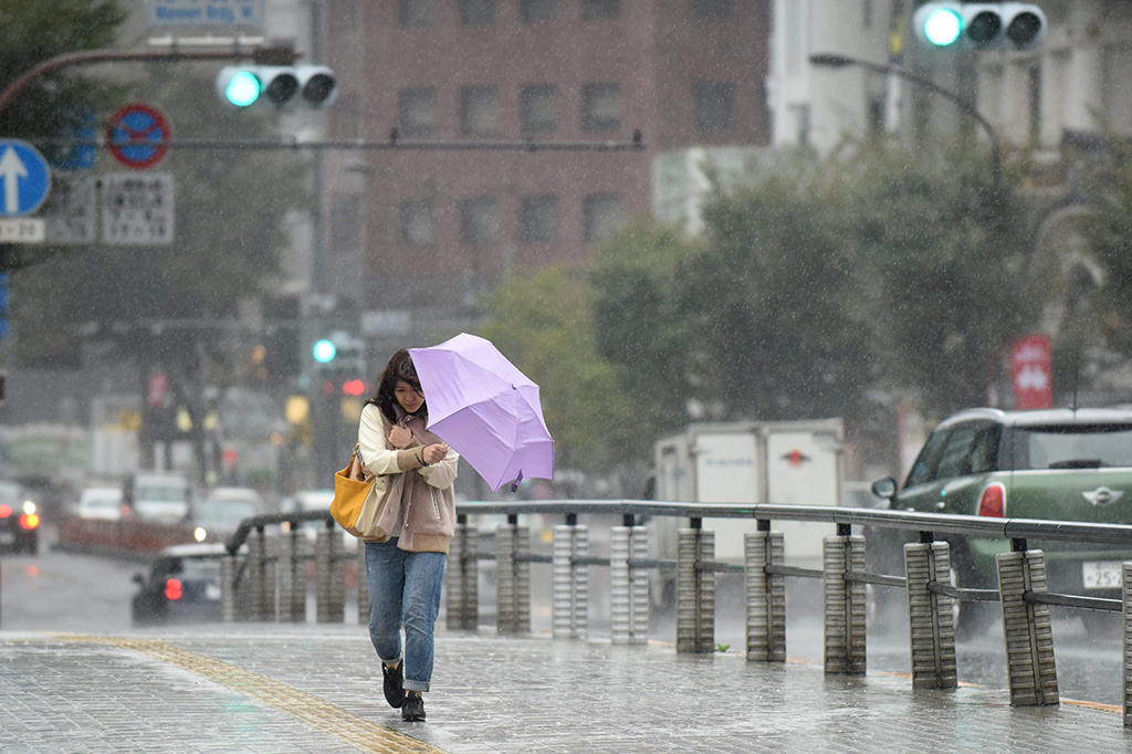 Warga di Tokyo tampak mengenakan payung untuk menahan guyuran air hujan.