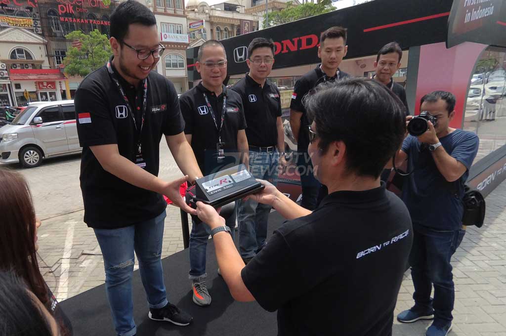 Proses penyerahan dilakukan langsung di samping mobil yang dikemas ala replika diecast.