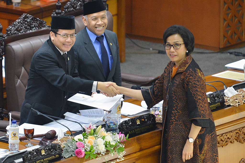 Menteri Keuangan Sri Mulyani berjabat tangan dengan pimpinan rapat paripurna Taufik Kurniawan (kiri) disaksikan Wakil Ketua DPR Agus Hermanto saat menyerahkan laporan pandangan pemerintah saat Rapat Paripurna DPR ke-10 di Kompleks Parlemen, Senayan, Jakarta, Rabu (25/10/2017).
