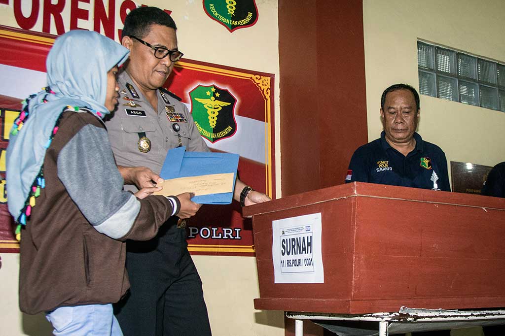 Kabid Humas Polda Metro Jaya Kombes Argo Yuwono (kedua kiri) menyerahkan peti jenazah Surnah korban kebakaran gudang petasan, kepada Suti, orang tua korban di Posko Post Mortem, RS Polri Sukanto Kramat Jati, Jakarta, Jumat (27/10). ANTARA/Aprillio Akbar 