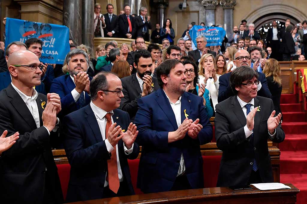 Presiden Catalan Carles Puigdemont (kanan) bertepuk tangan bersama anggota kabinetnya Oriol Junqueras (kedua kanan), Jordi Turull (ketiga kanan) dan Raul Romeva (kiri) setelah parlemen Catalonia memilih untuk menyatakan kemerdekaan dari Spanyol.  AFP/Lluis Gene
