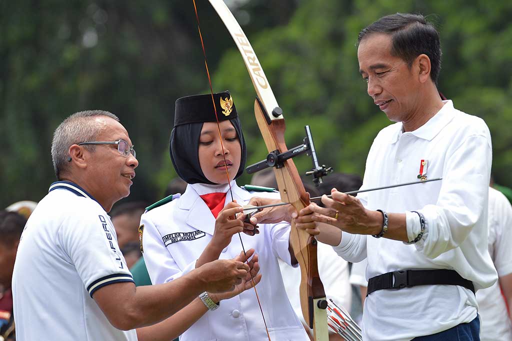 Presiden mengajari seorang anggota Paskibraka cara memanah. Sebelumnya Presiden telah memanah dan mengenai sasaran berwarna biru.