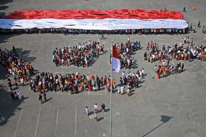 Dosen dan mahasiswa membentuk formasi delapan pulau Indonesia dan membentangkan kain merah putih saat peringatan Hari Sumpah Pemuda di Universitas Surabaya, Surabaya, Jawa Timur. Peserta mengenakan pakaian adat untuk menunjukkan berbeda latar belakang, budaya, agama, etnis, tapi tetap satu kesatuan. ANTARA/Umarul Faruq