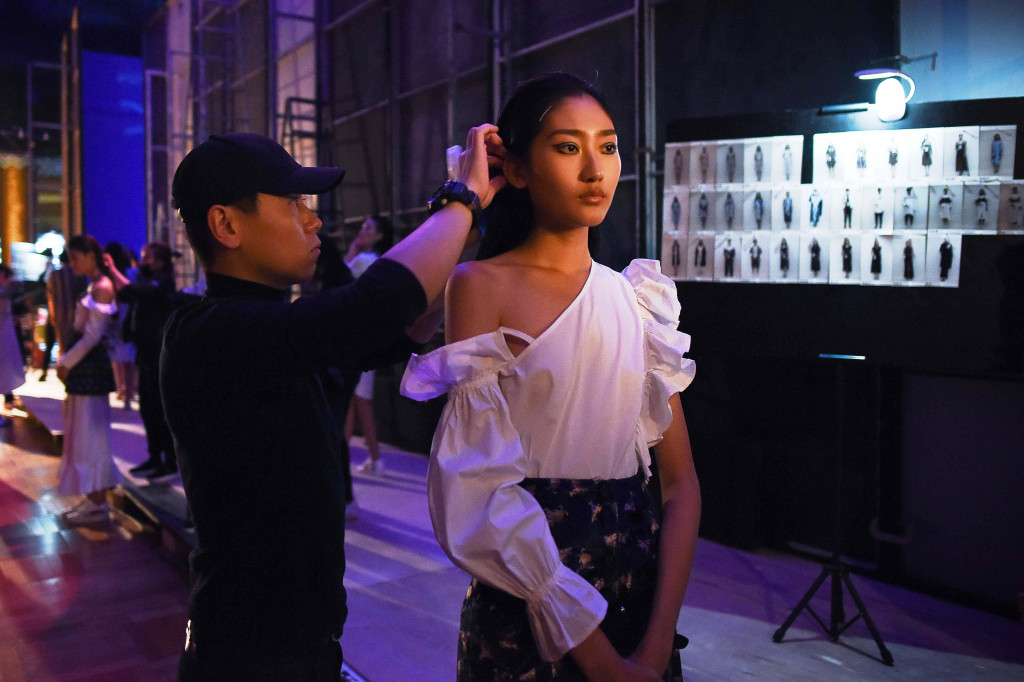 Memperbaiki tatanan rambut sebelum masuk antrian siap naik catwalk. 