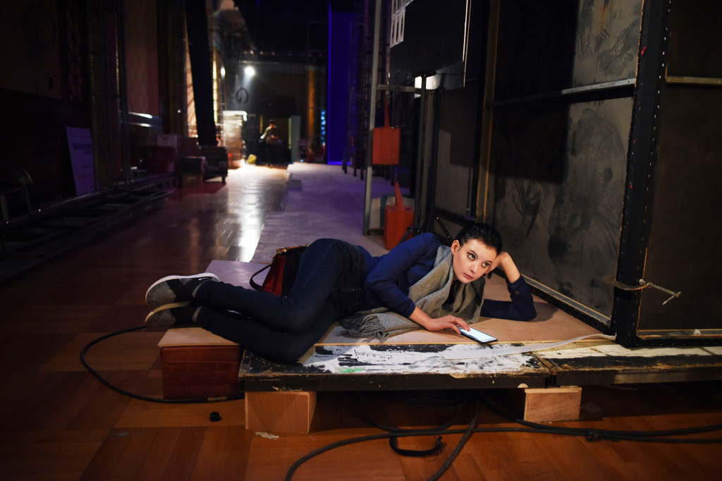 Seorang peragawati lain mengisi kesempatan beristirahat dengan bermain gadget. 